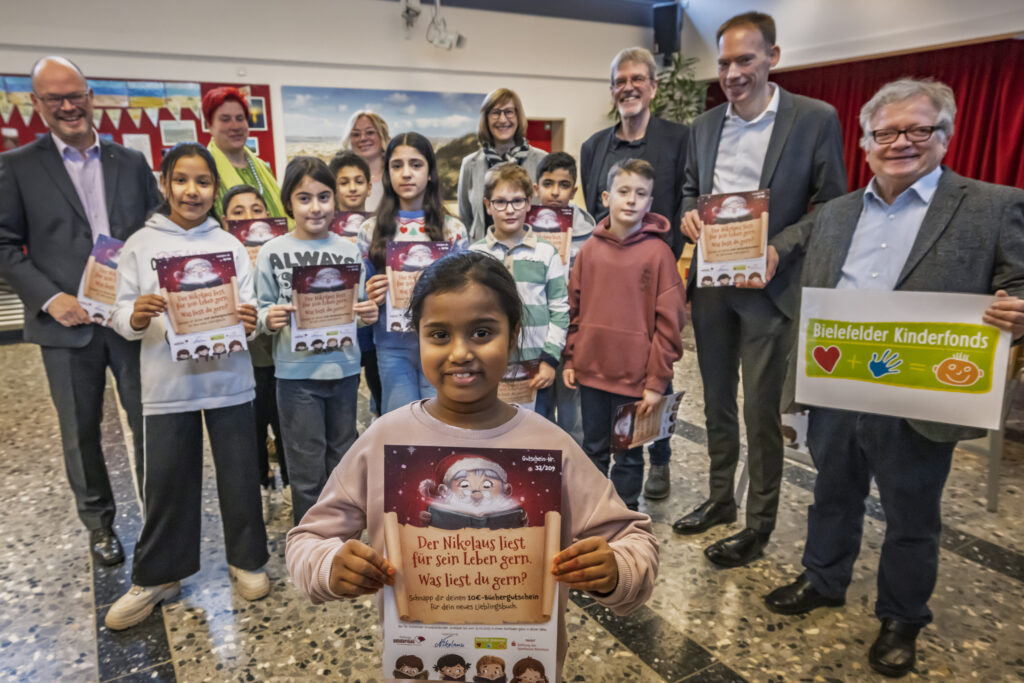 zu sehen auf dem Foto:
Ashvika aus der Klasse 4A freut sich über ihren Buchgutschein, genauso wie ihre Mitschüler:innen und (v.h.l.): Stefan Dwilies (Vorstand Stiftung Sparkasse Bielefeld), Claudia Fischer (Schulleitung), Sophia Rettig (Schulsozialarbeiterin), Brigitte Weidenbach (Bereichsleitung soziale Arbeit an Schulen), Norbert Burmann (Vorstand Stiftung Solidarität), Dr. Jörn Stöppel (Vorstand der Stiftung Sparkasse Bielefeld) und Franz Schaible (Stiftung Solidarität)  